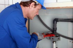 A Potomac Plumber tightens a plumbing line